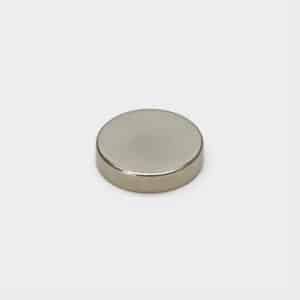 A nickel plated disc-shaped strong magnet laid flat on white desktop, with slightly rounded corners.