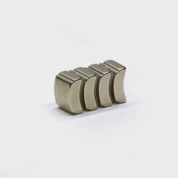 Stack of four small rare earth arc magnets with silver nickel plating, laid flat on their sides.