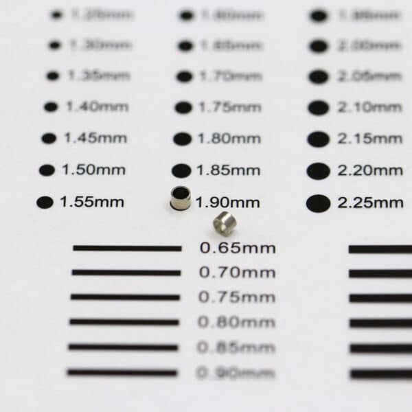 Two mini neodymium cylindrical magnets placed on a precision size estimation chart.