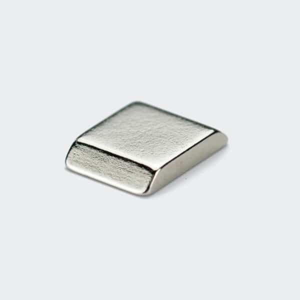 A tiny ladder-shaped rare earth magnet with a smooth trapezoid shape, silver nickel plating surface treatment.