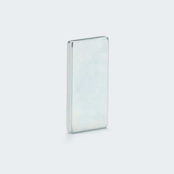 A thin rectangular rare earth magnet with matt blue zinc plating, vertically placed on a white desktop.