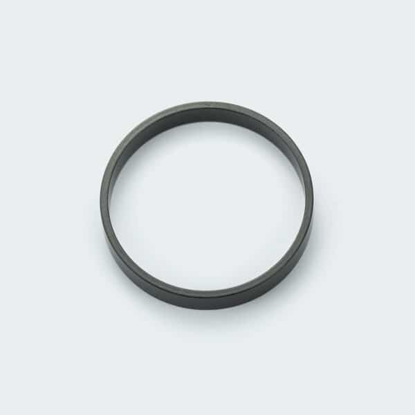 A black coated strong ring magnet with 22 poles by its inner diameter, laid on a white desk.